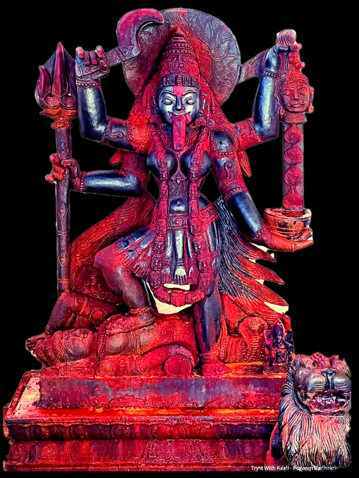 Red and dark sculpture of a deity with a trident and lion